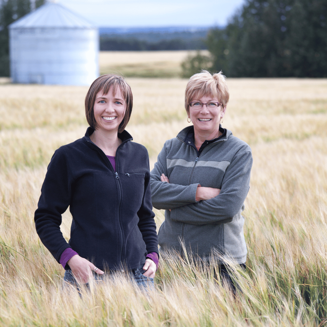 photo of two women standing in a wheat field