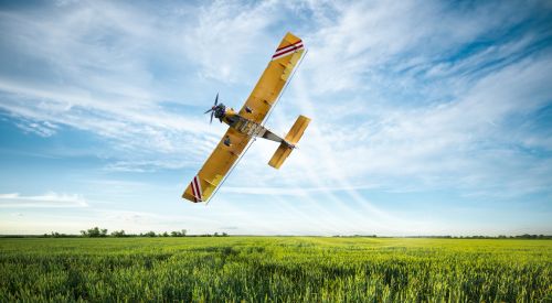 Crop duster flies over fields